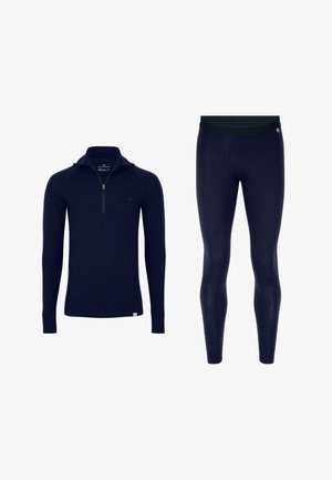 Marinblå termotröja med dragkedja i kragen och långa ärmar, kombinerad med matchande tajta leggings. Mjuk textur, minimalistisk design, utan mönster.