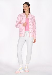 Roze bomberjack met hartjespatroon, geribbelde boorden, gecombineerd met grijze joggers en meerkleurige sneakers. Soepele stof met een relaxte pasvorm.