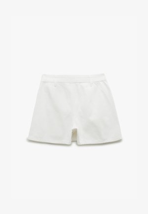 Pantaloni corti bianchi in cotone con un design aderente, dotati di una zip, due tasche frontali e una texture liscia. Dettagli cuciti lungo i bordi.