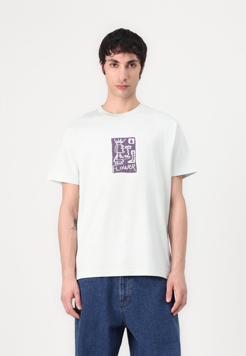 T-shirt en coton gris clair avec un col rond et des manches courtes, arborant un motif de fleur abstraite violette sur le devant.
