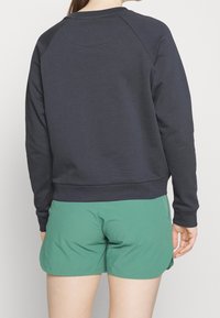 Sudadera de la marina con mangas raglán, dobladillo y puños de canalé, combinada con pantalones cortos verdes. Textura suave, diseño casual y acabado liso.