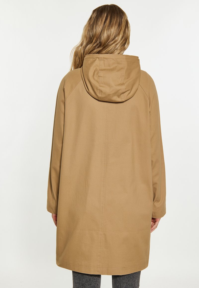 Manteau beige à capuche avec une coupe décontractée, présentant une coupe droite, des manches longues et des détails de couture. Fabriqué dans un matériau lisse et léger.