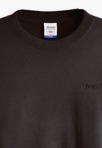 Felpa nera girocollo in tessuto morbido, con polsini e orlo a costine. Logo ricamato sul davanti con filo nero abbinato.