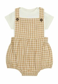 Lühikese varrukaga kreemjas särgis, mis on peidetud helepruunist gingham-ruudulises üleüldises, millel on reguleeritavad rihmad, puidust nööbid ja elastsed sääreava.
