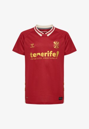 Rød sports-trøje med korte ærmer. Har en V-hals krave, gyldne logoer og et struktureret stof. Teksten lyder "tenerife!" i fede gyldne bogstaver.