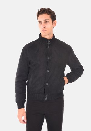 Giacca bomber nera in morbido suede con colletto alto, polsini a coste e sei bottoni di chiusura. Presenta una superficie liscia e una vestibilità rilassata.