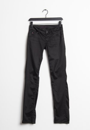 Jean skinny en denim noir à la texture lisse, design cinq poches, fermeture par bouton, suspendu sur un cintre noir contre un fond blanc.