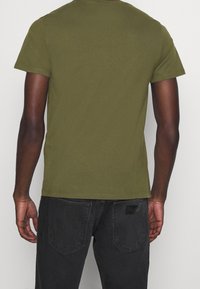 Olivově zelené tričko s krátkým rukávem, přiléhavého střihu, vyrobené z měkké bavlny, s kulatým výstřihem a rovním lemem.