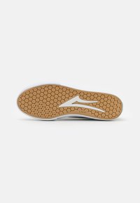 White sneaker sole with a hexagonal texture, brown rubber detailing, and a subtle white logo accent. Lightweight design for grip and support.