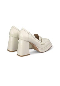 Chaussures à plateforme en cuir verni blanc avec des talons carrés épais et un design à bout fermé, présentant des détails de couture subtils.