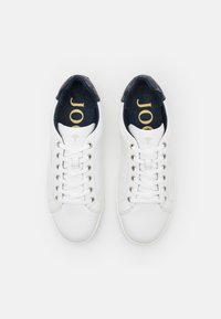 Weiße Ledersneaker mit glatter Textur, runder Spitze und flachen Schnürsenkeln. Das Innere verfügt über eine marineblaue Einlegesohle mit goldfarbenem Branding. Silberne Ösen und Akzente.