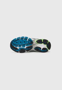 Running shoe sole with blue, black, and green rubber tread patterns on a white background.