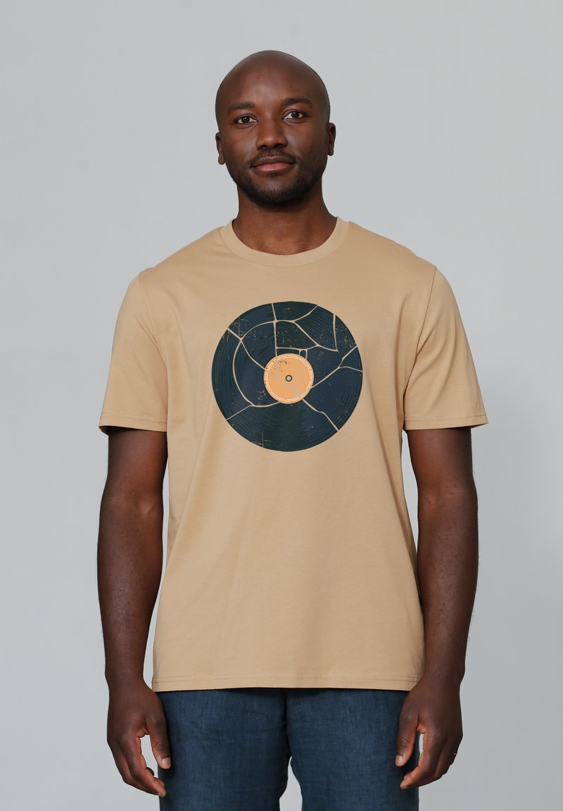 Beige t-shirt met een centraal grafisch ontwerp van een gebroken vinylplaat in donkerblauw met een oranje label, gemaakt van zachte katoen.