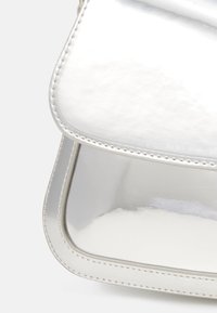 Borsa a tracolla in metallo argenteo con una finitura liscia e lucida, patta arrotondata e bordi cuciti. Design compatto senza hardware visibile.