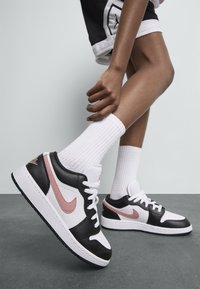 Nike Air Jordan kedas ir ar baltu un melnu ādas augšdaļu, rozā akcentiem, auklām un teksturētu gumijas zoli.