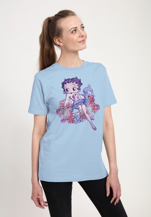 Lys blå bomulds t-shirt med et grafik af en tegneseriefigur omkranset af roser, med lilla og lyserøde accenter. Korte ærmer og rund halsudskæring.