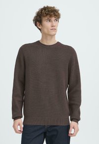 Suéter de punto marrón con cuello redondo y mangas largas. Presenta una tela texturizada y detalles acanalados en los puños y el dobladillo.