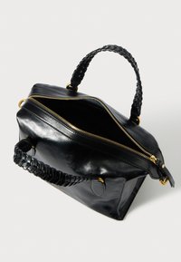 Mustast nahast käekott punutud sangaga, kullavärvilise luku ja metallsete detailidega. Avatud, sisemust näitamas. Sile tekstuur ja ristkülikukujuline vorm.