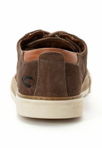 Brune ruskinds sneakers med en tan læder hælklap, hvid gummisål og en sort logoaccent på siden. Tekstureret og lavskåret design.