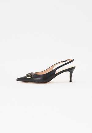 Zwarte leren slingback pump met spits toelopende neus, middelhoog dun hakje en decoratieve ronde gesp op de neus.