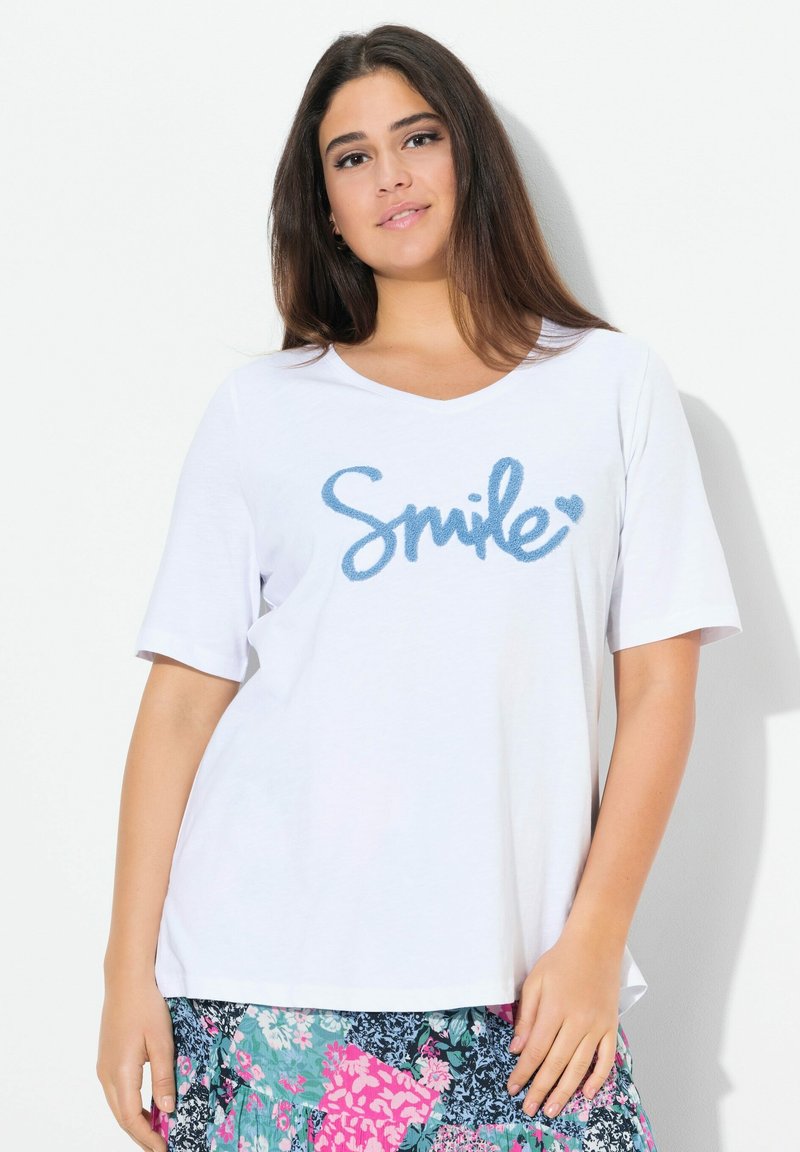 Bílý krátký rukáv T-shirt s modrou grafikou "Smile" v kurzívě na přední straně. Měkká tkanina s volným střihem.