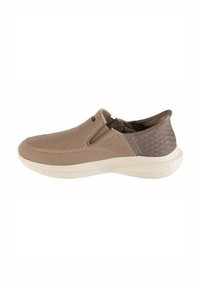 Beige Slipper mit einem strukturierten Strickoberteil, elastischen seitlichen Einsätzen und einer glatten, leichten Sohle. Die Ferse weist ein dezentes geometrisches Muster auf.