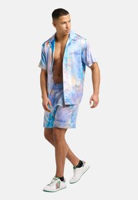 Short-sleeve collared shirt and shorts set in glossy pastel blue fabric, featuring vibrant abstract patterns and elastic waistband.
