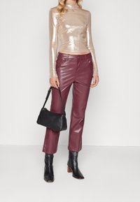 Glänsande guld långärmad topp, vinröda fusk läderbyxor, svart handväska och svarta klackade ankelstövlar med fyrkantig tå.