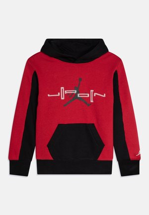 Rød og sort hættetrøje med sort frontlomme, sorte ærmer, en hætte og et centralt Jumpman-logo med ordet "Jordan" på brystet.