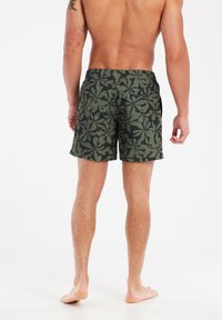 Muške kupaće gaće, tamnozelene boje s uzorkom lišća, elastičan pojas, dužina iznad koljena, lagani materijal s teksturiranom površinom.