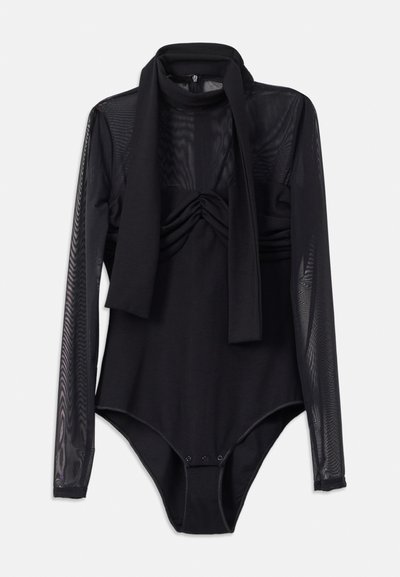 Sort langærmet bodystocking med netoverlap, samling foran og bindebånd ved halsen. Trykknapslukning nederst.