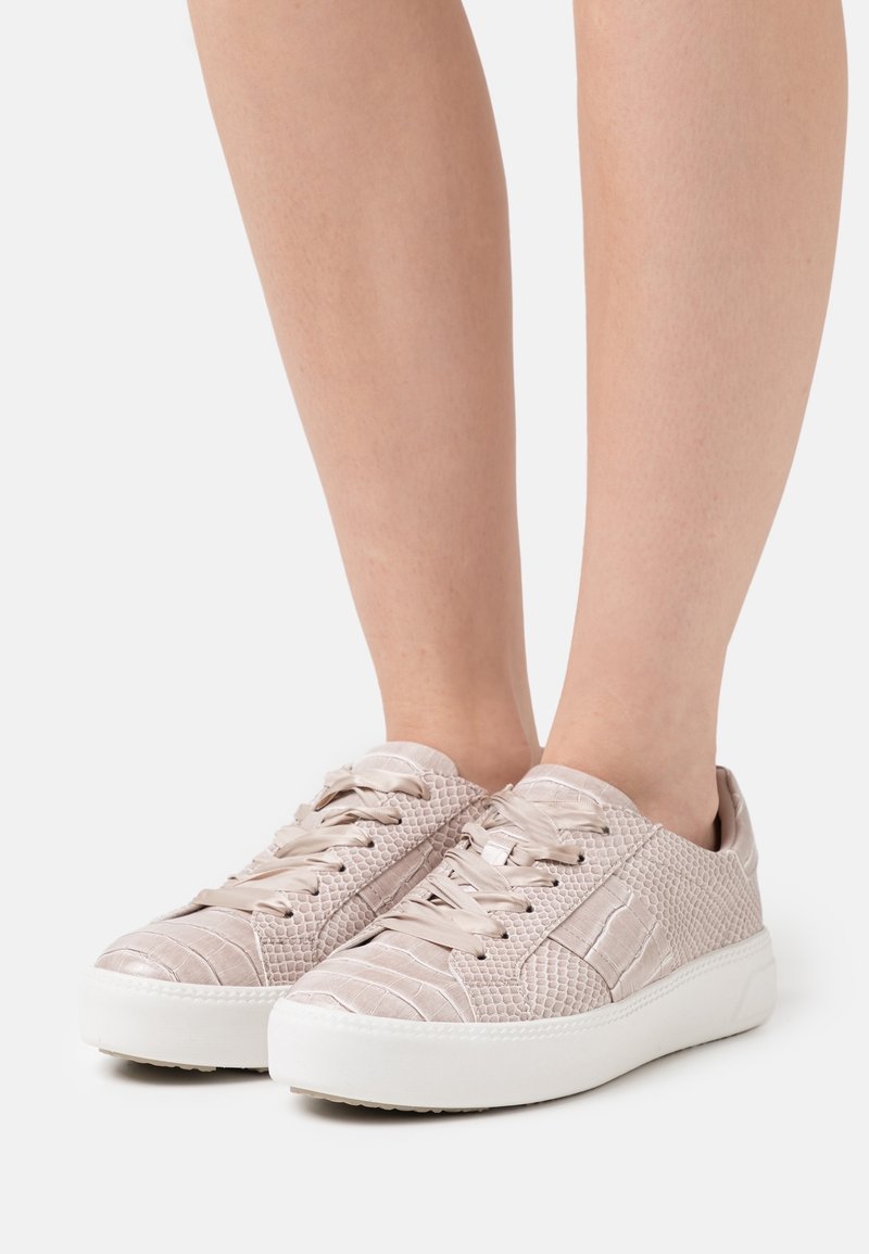 Light pink sneakers with a textured, faux-crocodile finish, featuring flat laces, a white rubber sole, and subtle stitching details.