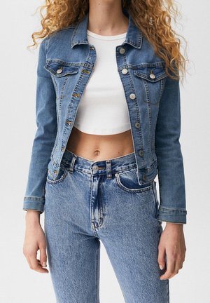 Leren spijkerjack in lichtblauw met een cropped ontwerp, voorzien van twee borstzakken, zilveren knopen en een klassieke kraag. Gedragen boven een wit top.