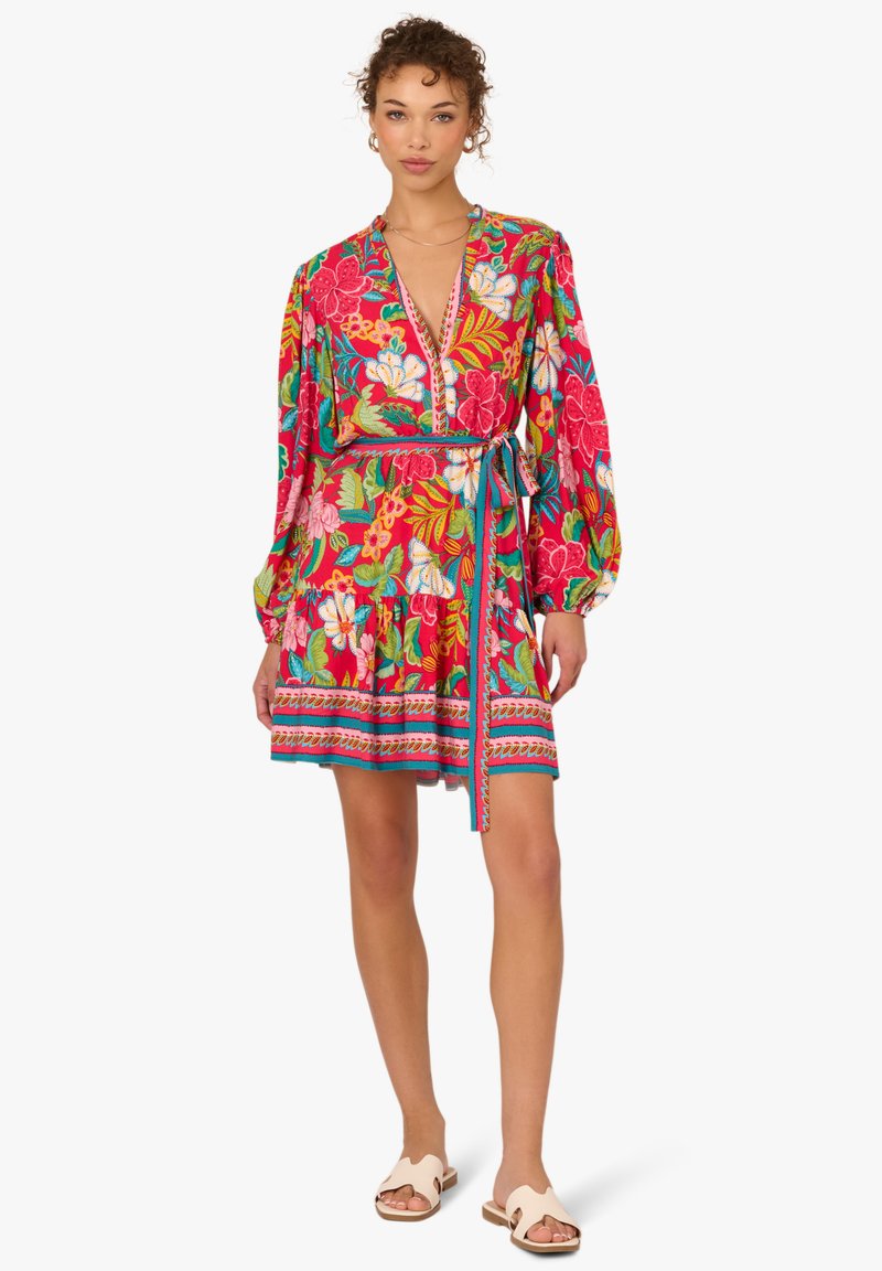 Blumenkleid mit tiefem V-Ausschnitt, langen Puffärmeln und tailliertem Bindegürtel. Farben sind Rot, Pink und Grün, mit einem gemusterten Saum.