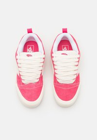 Paire de baskets Vans roses et blanches avec des lacets blancs, vues de dessus sur un fond blanc.