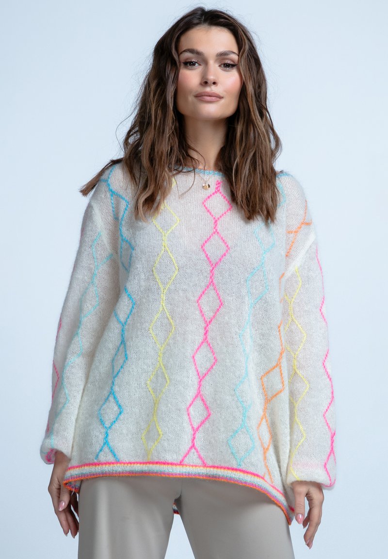 Biały, oversize'owy sweter z kolorowymi wzorami w romby w odcieniach różu, niebieskiego i żółtego. Charakteryzuje się miękką, puszystą teksturą oraz prążkowanym dołem.