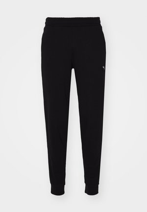Joggers negros de tejido suave, con cinturilla elástica, piernas ajustadas y un pequeño parche con el logo en el costado.