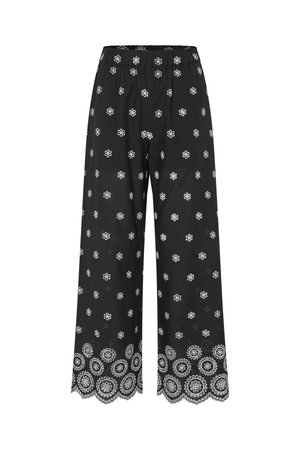 Mustat leveälahkeiset housut, joissa valkoinen kukkakirjailu sijoittuneena kauttaaltaan, ja yksityiskohtaiset kukkakuvioinnit aaltoilevan helmuksen kohdalla.