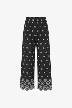 Μαύρο παντελόνι με φαρδιά ποδός και λευκή λουλουδένια κεντητική διάσπαρτη σε όλο το ύφασμα, καθώς και λεπτομερή λουλουδένια σχέδια κατά μήκος της κυματιστής τελειώματος.