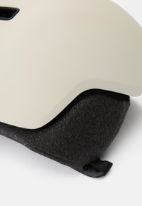 Valge kiiver sileda välispinnaga ja tumeda, tekstureeritud polstriga põhjas. Sisaldab reguleerimisrihma ja kindlat istuvust.