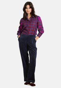 Sarkana un purpursārta kvadrāta raksta krekls ar puff piedurknēm un ziedu izšuvumiem. Jūras spēku krāsas corduroy bikses ar taisnu piegriezumu un sānu kabatām.