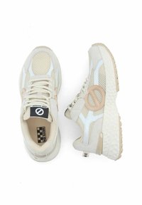 Baskets beige clair en matière de filet et cuir, avec des accents blancs et un logo circulaire, semelle texturée et design à lacets.