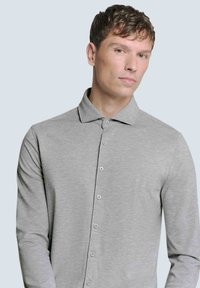 Graues langärmeliges Shirt aus weichem, strukturiertem Stoff. Mit Kragen, Knopfleiste und taillierter Passform.