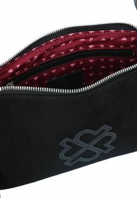 Borsa nera in suede con apertura con zip, interno bordo con una fodera a motivi e un logo in rilievo ben visibile sulla parte anteriore.