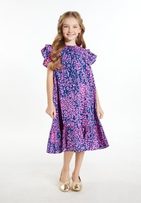 Gėlių raštais, tamsiai mėlynas su rožiniais leopardų taškais suknelė, raukšlėtomis rankovėmis ir platėjančiu sijonu; derinama su blizgiais auksiniais bateliais.