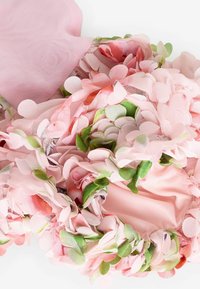 Florales Accessoire mit weichem, rosafarbenem Mesh und geschichteten Stoffblütenblättern in verschiedenen Rosatönen und Grüntönen. Strukturiert, mit einem gerafften Saum.