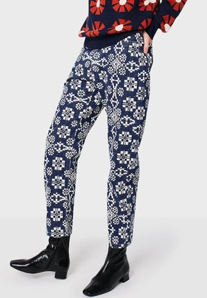 Navy blue and white patterned pants worn with a black and red floral sweater and black ankle boots on a plain background.