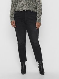 Calças de ganga pretas com um corte direito, de peso médio, design de cinco bolsos e fecho por botão. Combinadas com uma blusa de manga longa floral.