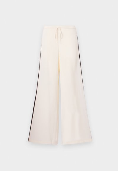 Krém színű, bő szárú nadrág sima anyagból, húzózsinórral ellátott derékkal és kontrasztos sötét oldalcsíkokkal. Lapos fronthálós kialakítás, zsebek nélkül.