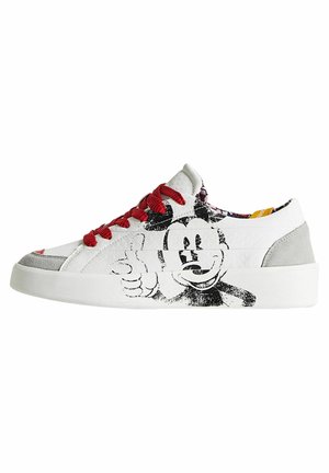 Baskets basses blanches avec des lacets rouges, des accents gris, et un grand personnage de dessin animé en noir et blanc faisant un pouce levé sur le côté.